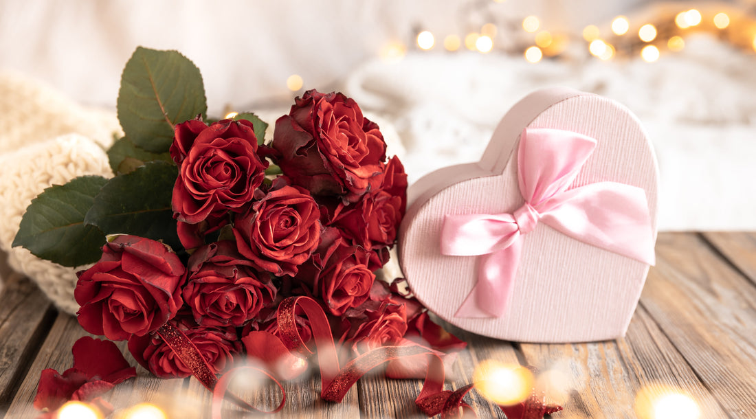 A bouquet of elegant red roses placed beside a heart-shaped gift box, symbolizing love, romance, and special celebrations. The image captures the timeless appeal of anniversary flower arrangements and thoughtful gifting.