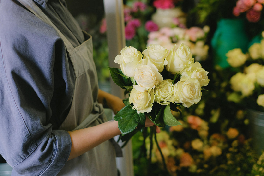 Local florist in Singapore holding a fresh white rose bouquet for flower delivery and gifting.